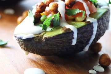 recipe image showing half an avocado stuffed with grilled chickpeas and drizzled with tahini and herbs