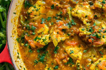 A hearty bowl of tasty Moroccan chicken stew view above and served in a traditional ceraminc dish with fres herbs to garnish on one side