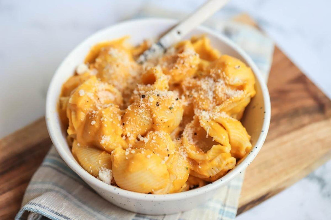 creamy healthy quick and easy pumpkin pasta in a white bowl with a wooden board underneath