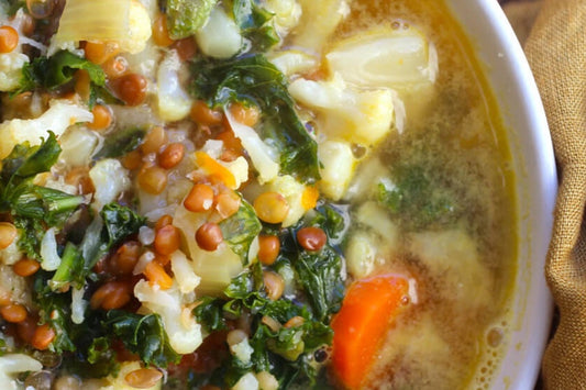 image from above of a white bowl filled with cauliflower, lentil and kale healthy detox soup