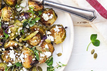 image of maple and mustard brussels sprouts topped with feta cheese and pumpkin viewed from above and served in a white dish