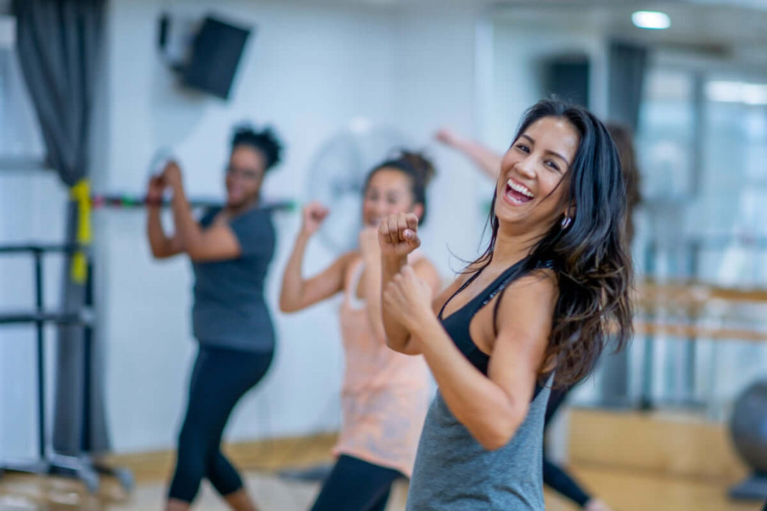 Image of women of mixed ages and backgrounds taking an exercise class and being happy and healthy and smiling whilst they exercise in the gym or studio