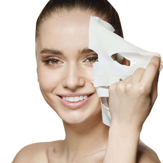 head shot of woman with dark hair pulling a sheet mask away from her face