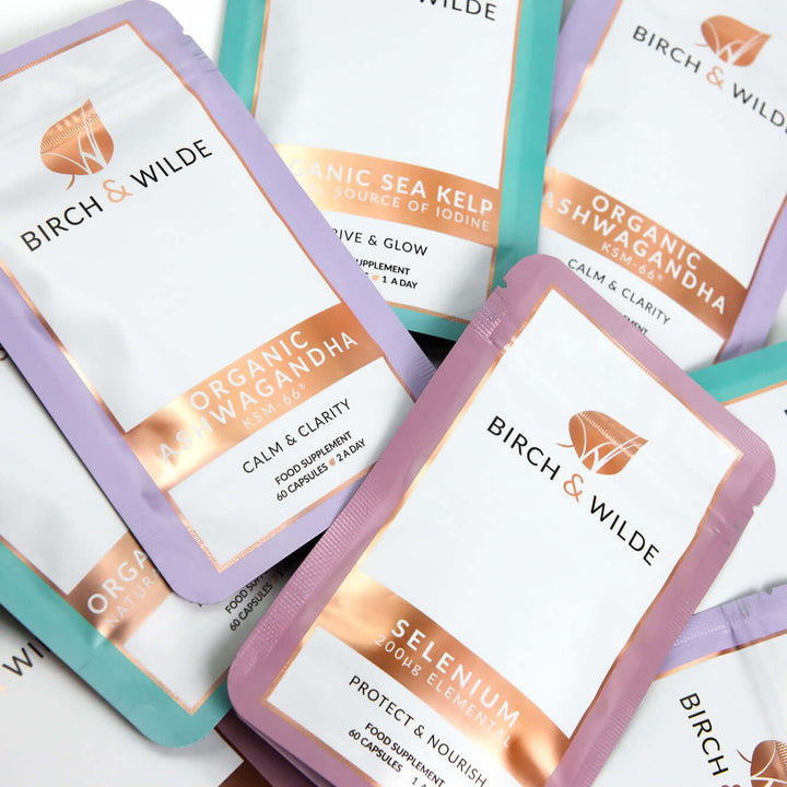 flat lay product shot of mixed supplement refill pouches from Birch & Wilde including organic sea kelp capsules, selenium capsules and organic ashwagandha ksm66 capsules