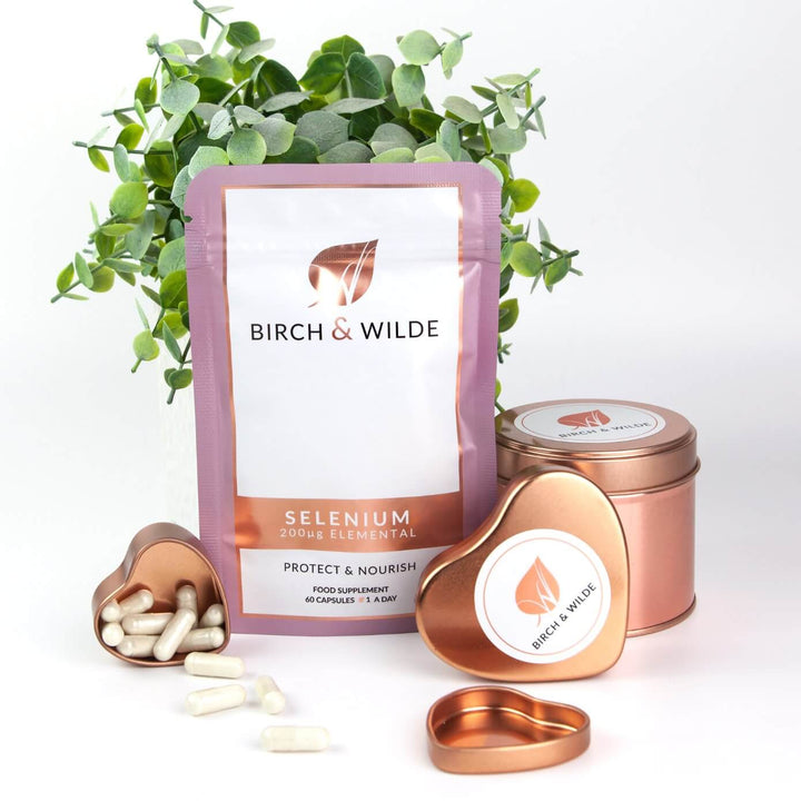  product lifestyle shot taken from the front of Birch & Wilde selenium health supplement capsule refill pouch with a green plant in the background